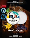 Beard balm container with branding and product details on a dark background with drinks.